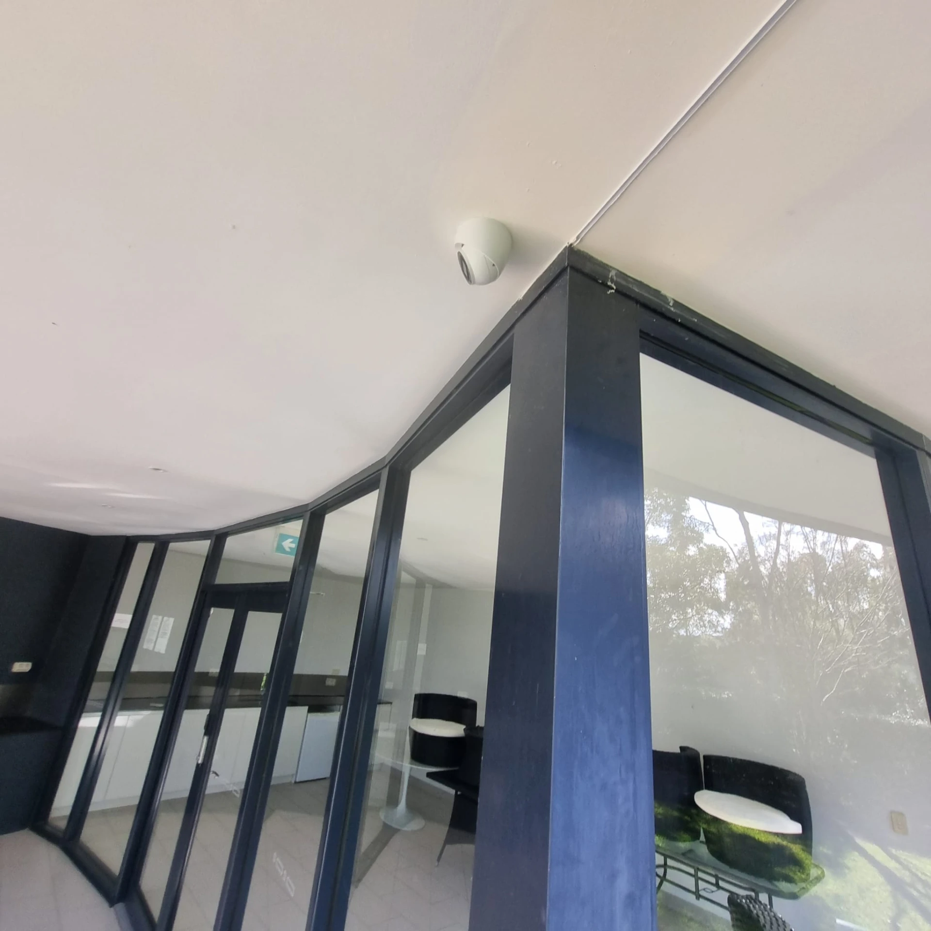 Discreet white dome camera above a glass entry